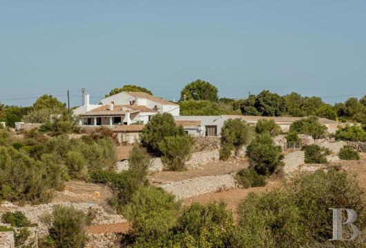 In Menorca, a rural estate built of marès stone, with its stables, old cheese dairy and woodland covering some ...